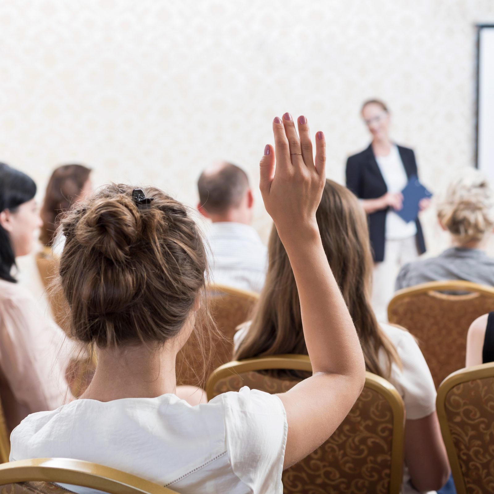 Photo of listener raising hand to ask question during seminar
